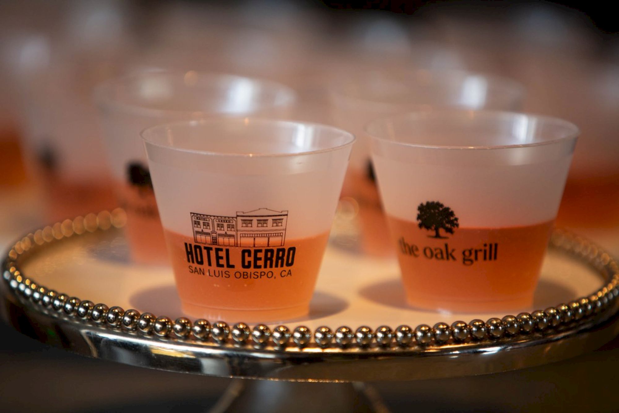 Several plastic cups with logos on a decorative tray, likely containing a beverage.
