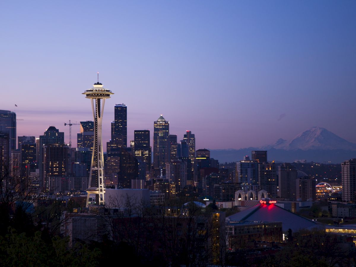 The image shows a city skyline at dusk with a prominent tower, surrounded by skyscrapers and a mountain in the background.